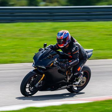 motorcycle rider on a road riding with black gear on and a red helmet
