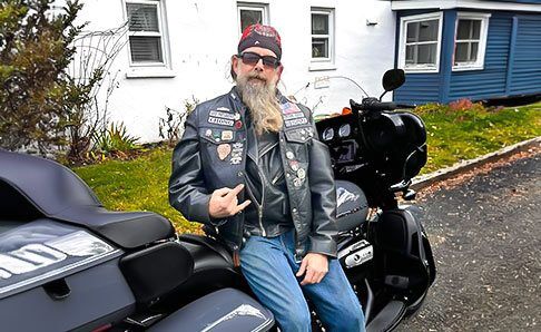 Biker leaning on his bike in front of house